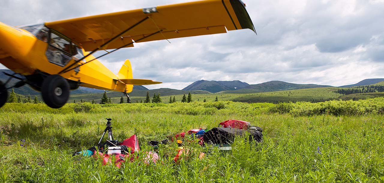 A plane taking off along side gear it's left on the ground in the Alaskan bush